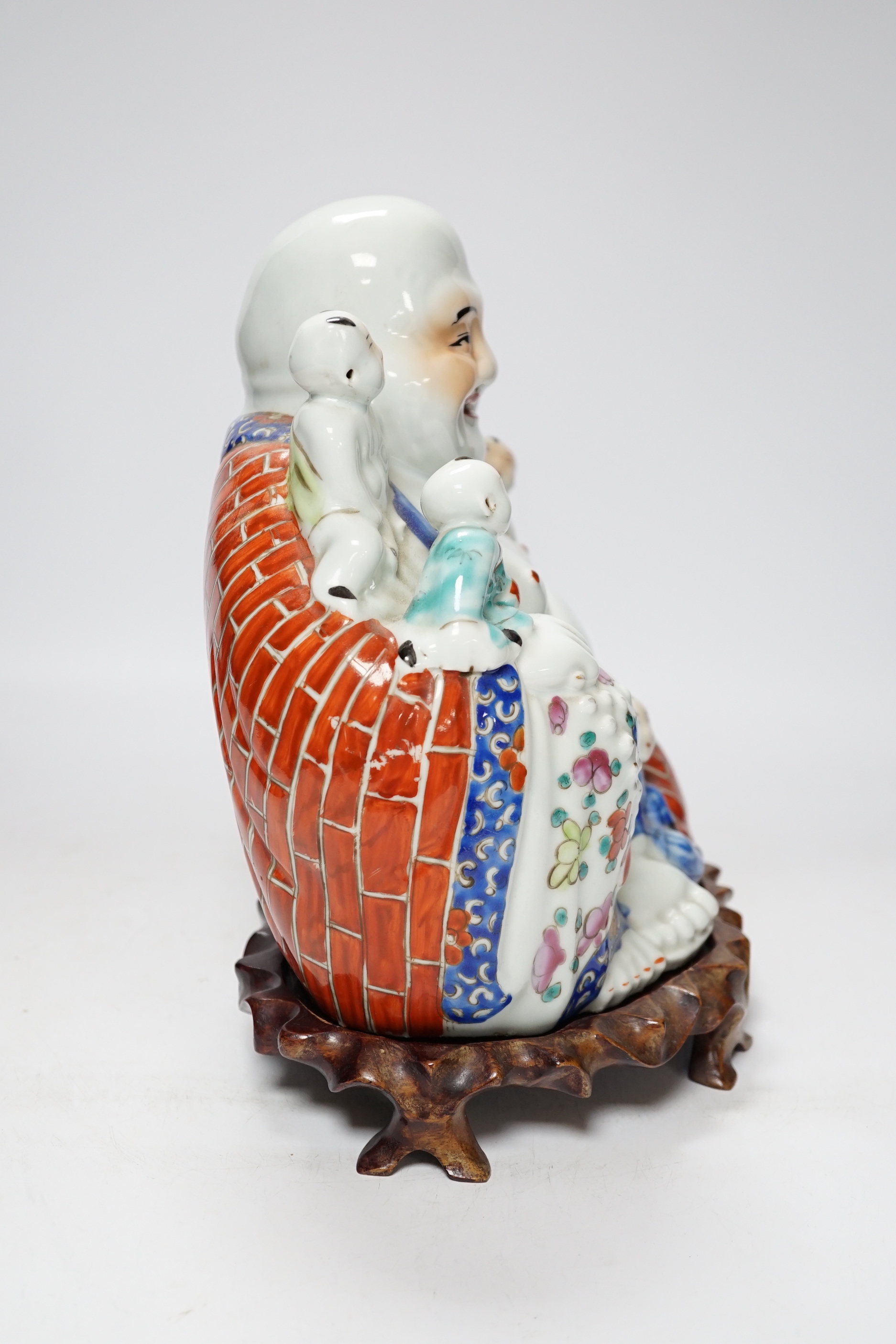A 20th century Chinese porcelain Buddha on hardwood stand, 28cm